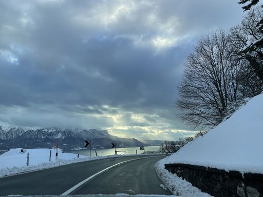 A narrow road through snowy Chatel Saint-Denis town by a frozen lake in Fribourg, Switzerland
