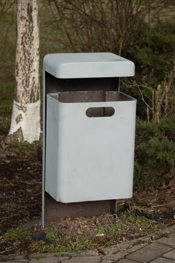 A white trash bin in a park