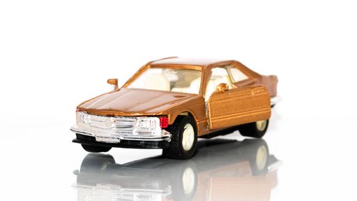 A brown toy vintage car on a white background