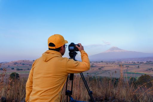 A back view of a young Mexican professional photographer with a camera capturing the beautiful landscape