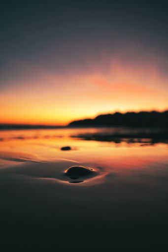 A vertical shot of a beach surrounded by the sea with long exposure during a beautiful sunset