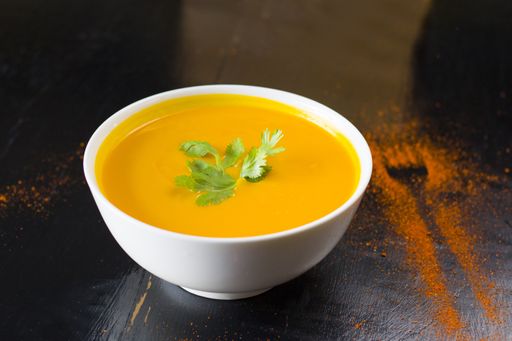 A closeup shot of an appetizing yellow pumpkin cream soup in the bowl on the restaurant's table