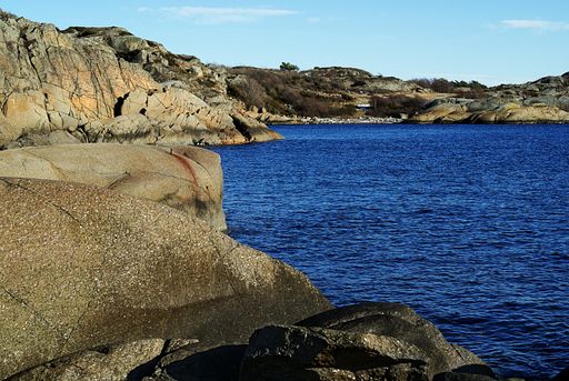 A high angle shot of the rocks on the shore of a blue lake in Stavern, Norway