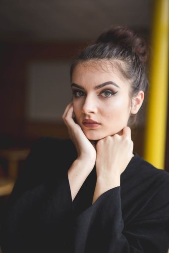 A young Bosnian woman with a bun hairstyle and makeup looking at the camera