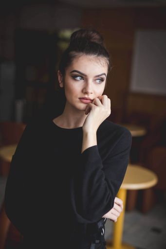 A young Bosnian woman with a bun hairstyle and makeup looking out of the window