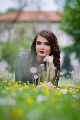 A young Bosnian woman laying on the dandelions in the park