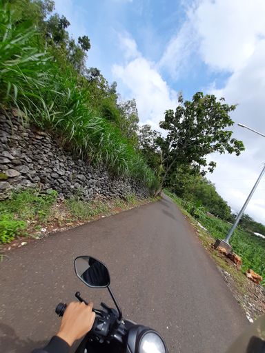 POV in over head shot from a motorbike driving on a narrow left-hand traffic village road on Java in Indonesia.