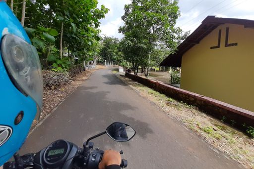 POV in over head shot from a motorbike driving on a narrow left-hand traffic village road on Java in Indonesia.