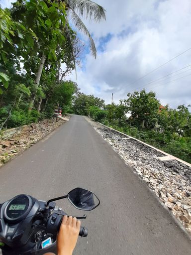 POV in over head shot from a motorbike driving on a narrow left-hand traffic village road on Java in Indonesia.