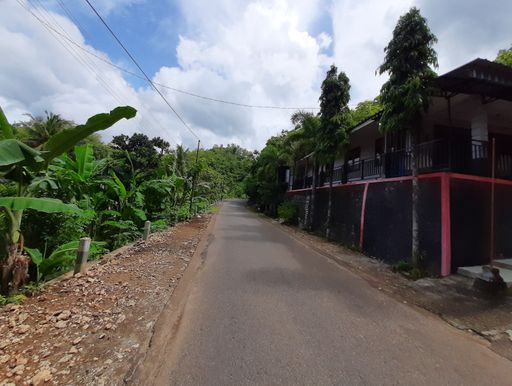 POV in over head shot from a motorbike driving on a narrow left-hand traffic village road on Java in Indonesia.