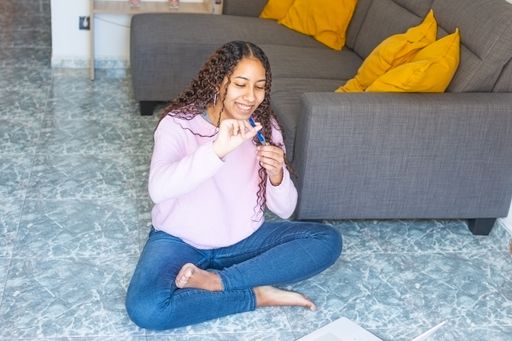 A Hispanic female sitting on the floor and looking at the pen in her hand