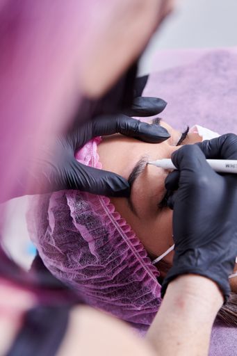 A beauty salon worker microblading the eyebrows of a client