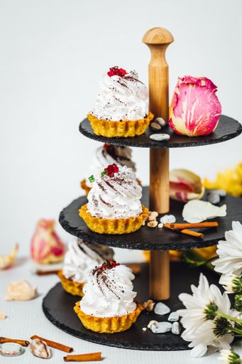 A vertical shot of various types of cakes and biscuits on a cake stand