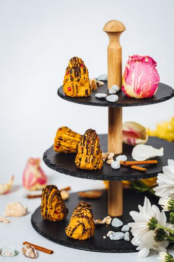 A vertical shot of various types of cakes and biscuits on a cake stand