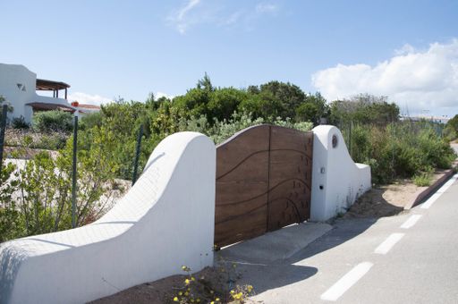 A closeup shot of  wooden gates in the middle of two white walls on the garden background