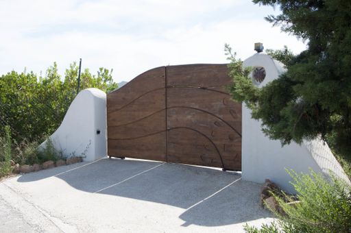A closeup shot of  wooden gates in the middle of two white walls on the sky background