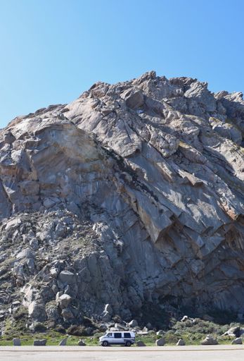 A Vertical photo of a retro Van parked next to Morro Bay Rock in Ca. as the van looks dwarfed in comparison March 3, 2021