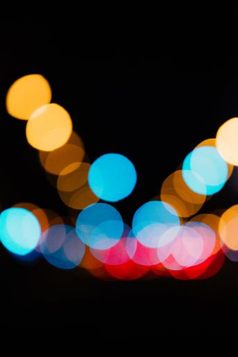 A vertical shot of beautiful colorful bokeh lights on a dark background