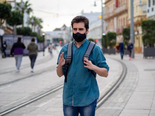 A Spanish male with face mask walking outdoors - concept of the new normal