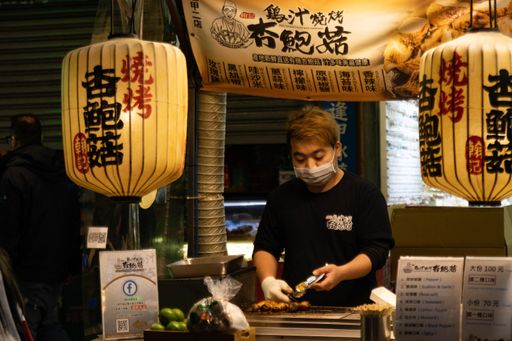 A Chinese man serves grilled food at Feng Chia Night Market in Taichung City in Taiwan - January 2020.