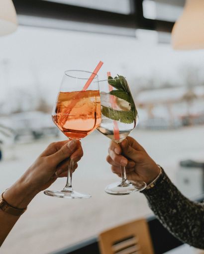 A close up Two people celebrating with cocktails in restaurant.
