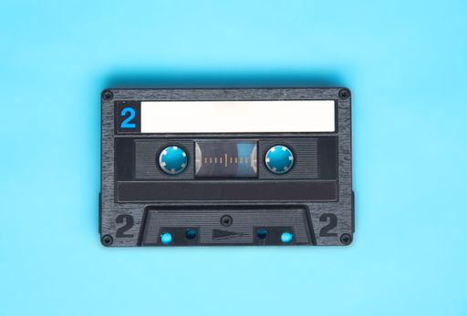 Retro audio cassette tape on turquoise background. Directly above view.