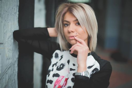 A sexy Caucasian blonde in a black and white shirt, looking at the camera while touching her hair