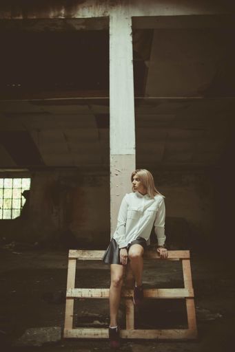An attractive Bosnian Caucasian woman sitting on a wood pallet in an old building