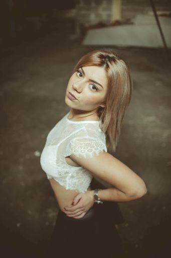 A vertical shot of a cute Caucasian blonde posing, looking up at the camera
