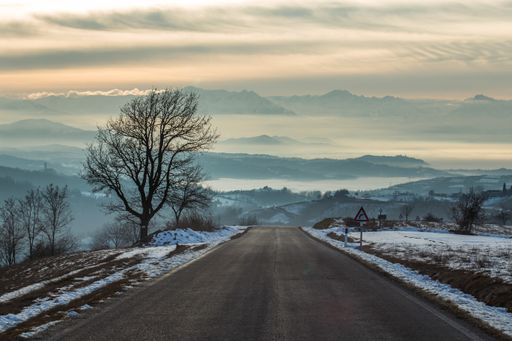 A road surrounded by rocks covered in the fog and snow under the sunlight in Italy