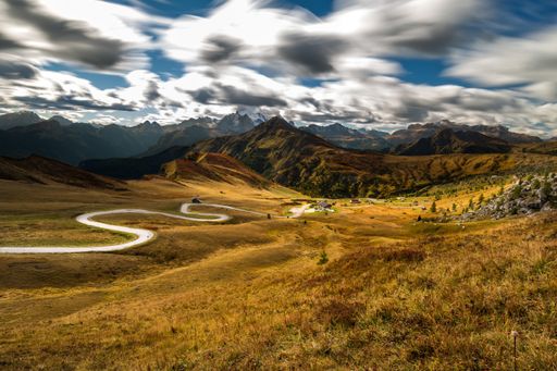 A field surrounded by rocks covered in greenery under the sunlight and clouds with a motion effect
