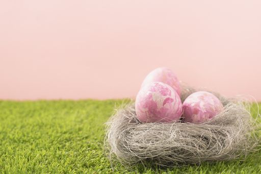 A soft focus of pink Easter eggs n a nest on a grassy lawn