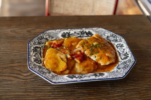A closeup shot of a chicken dish in flavorful sauce on a wooden table