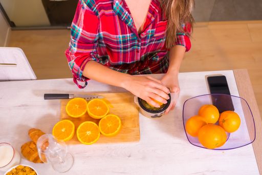 A blonde Spanish woman making orange juice for breakfast in her kitchen
