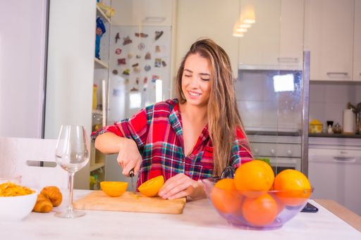 A blonde Spanish woman making orange juice for breakfast in her kitchen