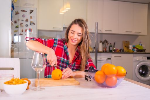 A blonde Spanish woman making orange juice for breakfast in her kitchen