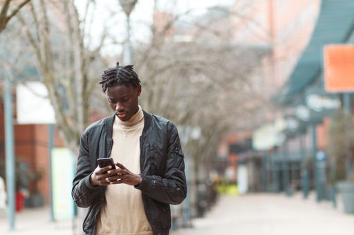 A young Afro-American guy using his phone in the streets of Lyon in France