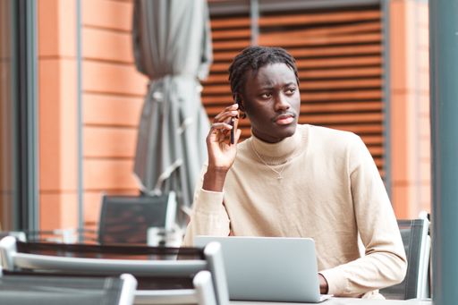A young Afro-American entrepreneur working on his laptop talking on the phone in Lyon, France
