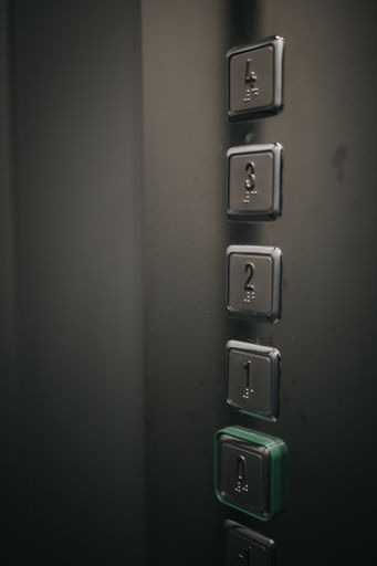 A vertical shot of an elevator buttons with numbers from 0 to 4