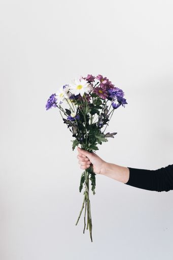 A vertical shot of woman's hand holding the flower composition bouquet isolated in white background.