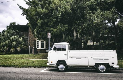 A white compact van parked on the road near the trees