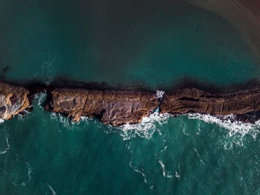 An aerial shot of cliffs surrounded by the sea under the sunlight - great for wallpapers