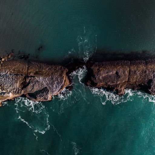 An aerial shot of cliffs surrounded by the sea under the sunlight - great for wallpapers