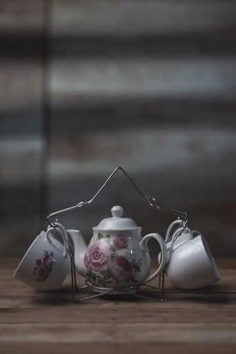An antique tea set consisting of a teapot and four cups on a wooden table