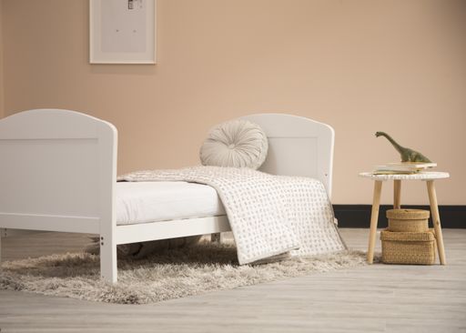 A shot of a minimalistic spacious bedroom with a little table and fluffy carpet under the bed.