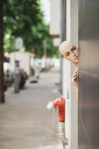 A vertical shot of a naked female mannequin near a black wall