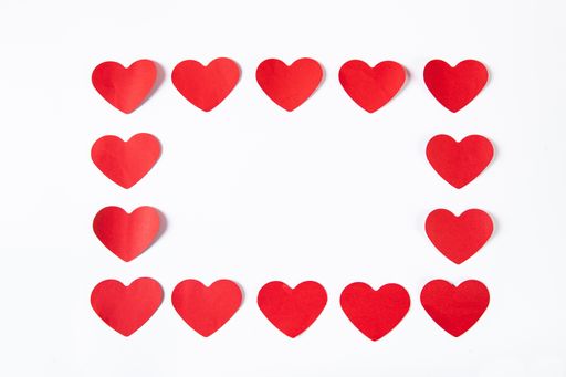 A high angle shot of red paper hearts shaped like a frame on a white surface