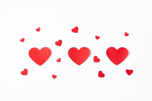 A high angle shot of big and small paper hearts on a white background