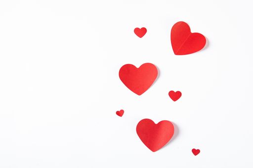 A high angle shot of big and small paper hearts on a white background