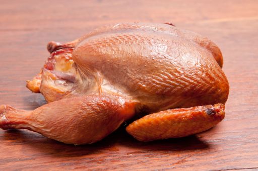 A closeup shot of smoked whole chicken on a wooden table